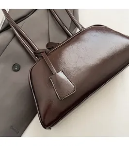 Detailed view of dark brown glossy wax leather boston bag on a grey suit jacket