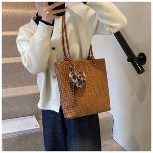 Close-up of brown woven tote bag texture with a leopard print heart plush keychain