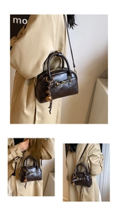 Detail of dark brown leather Boston bag with golden horsebit buckle and ball pendant