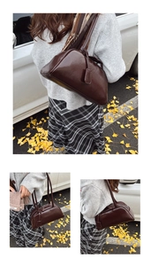 Detail of dark brown leather Boston bag with minimalist shoulder strap and tag