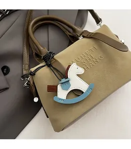 Dettaglio borsa bowling in pelle kaki con manici marroni e ciondolo a forma di cavallo