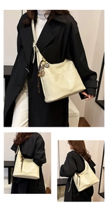 Détail du sac hobo en cuir crème avec bandoulière réglable et pendentif à pompon assorti