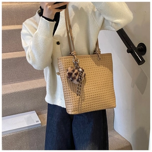 Detail of beige woven tote bag with heart-shaped leopard print pendant and slim straps