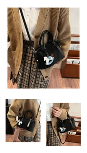 Dettaglio borsa bowling in morbida pelle nera con logo MUHETI SHI SHANG e ciondolo a cavallo
