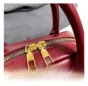 Close-up of premium gold-toned zipper and textured burgundy leather on the handbag