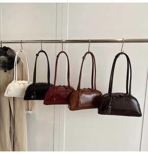 Row of minimalist Boston handbags in five colors hanging on a metal rack