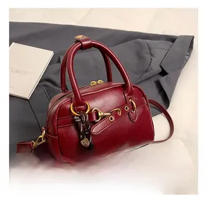 Close-up of deep red Boston bag with gold horsebit buckle and woven rope detail