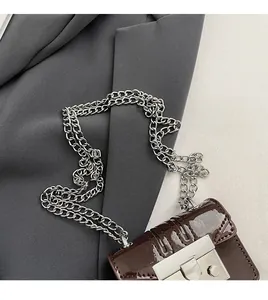 Detail of dark brown patent leather mini bag with silver chain and metal lock