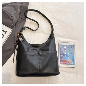 Vue détaillée du sac cabas en cuir noir vintage avec poches et breloque décorative