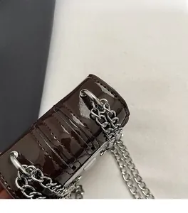 Detail of burgundy patent leather bag showing silver metal ring buckle and fine chain strap