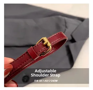 Detail view of burgundy leather adjustable shoulder strap with golden metal buckle