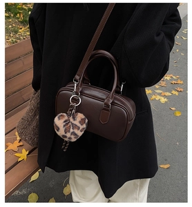 Detailed shot of a vintage brown handbag with a leopard print heart charm for winter fashion