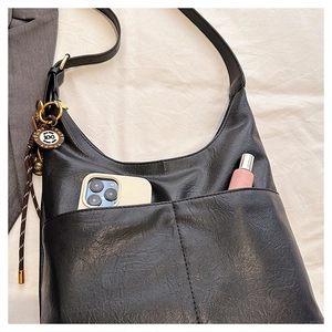 Detail view of large black tote bag front pockets showing phone storage and gold pendant