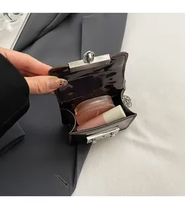 Detail view of the mini patent leather bag interior showing cosmetics and silver chain