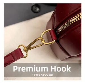 Detailed close-up of premium gold-toned metal hooks and zippers on a wine red leather bag