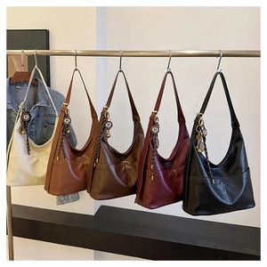 Row of five colorful PU leather hobo tote bags featuring elegant tassel charms on hangers