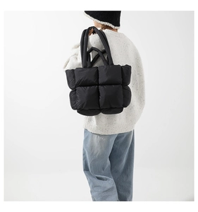 Détail du sac cabas matelassé noir avec surpiqûres carrées et doubles poignées