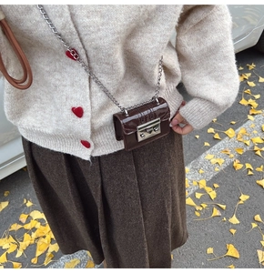 Detailed close-up of a mini brown leather chain bag with glossy animal texture and metal lock