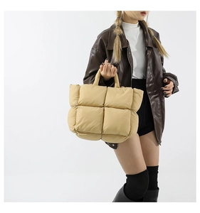 Vue latérale du sac à main matelassé beige avec poignées épaisses sur un modèle