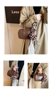 Detail of a brown vintage boston bag with a leopard print heart charm and metal buckles