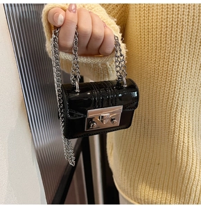 Close-up of mini black patent leather bag with silver chain and metal lock