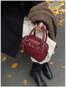 Vue détaillée du sac boston en cuir bordeaux avec finitions dorées et feuilles d'automne