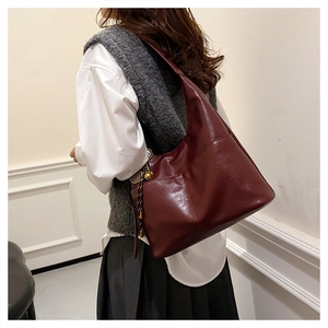 Detail view of large burgundy faux leather tote bag worn by model on shoulder
