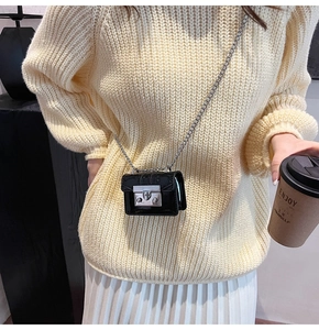 Mini black lychee textured crossbody bag with silver clasp and chain on a knit sweater