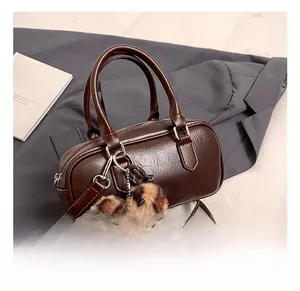 Detail showing deep brown Boston bag texture with leopard print fur ball charm