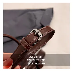 Detail of adjustable dark brown leather shoulder strap with silver buckle and fine stitching