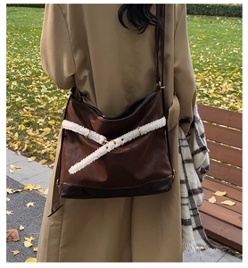 Detail of vintage brown large shoulder bag with white plush strap on model in autumn park