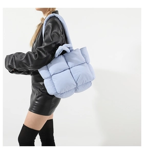 Sac fourre-tout matelassé bleu clair porté avec une veste en cuir noir pour femme