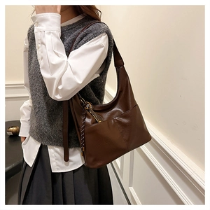 Détail du sac hobo en cuir marron foncé avec texture fine et breloque tressée