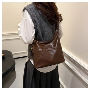 Brown faux leather tote bag with vertical stitching and unique racket-shaped charm