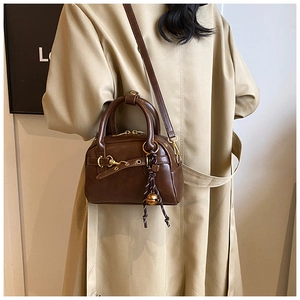 Détail d'un sac Boston rétro en cuir marron foncé avec ornements dorés élégants