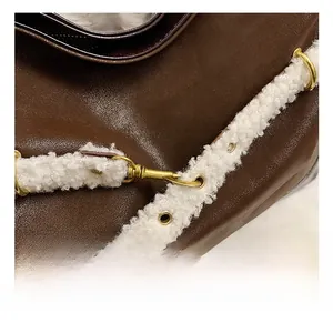 Close-up of brown pebbled leather texture with white faux fur trim and gold metal hardware