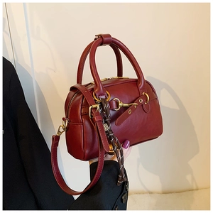 Détail du sac Boston en cuir rouge foncé avec anneau métallique doré et boucle chic