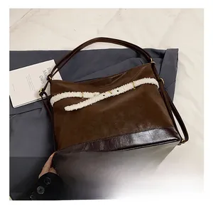 Detail of dark brown tote bag featuring matte finish and white plush decorative strap