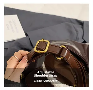 Detailed macro view of adjustable brown leather shoulder strap with gold metal buckle