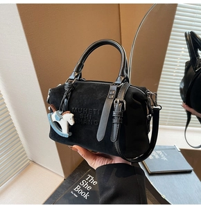Detail of black suede Boston bag with MUHETI SHI SHANG embossing and horse charm