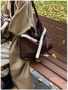 Outdoor shot of a vintage brown leather tote with white fleece trim on a park bench