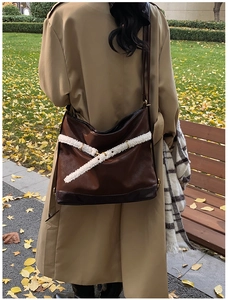 Close-up of brown leather tote bag with white shearling trim and metallic buckles