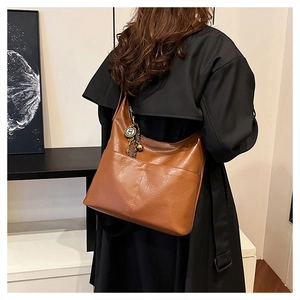 Détail du cabas en similicuir caramel avec poche extérieure et breloque en métal rétro