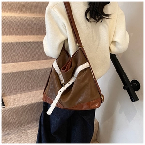 Detail of the large brown matte leather tote bag with white faux shearling trim accents