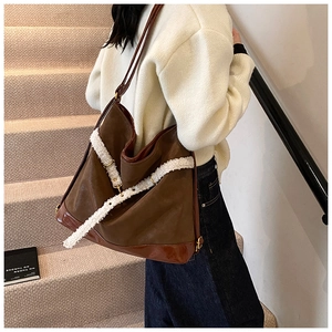 Detail of a large brown leather tote bag with white shearling trim and metal buckles