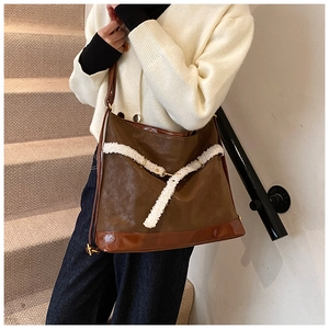 Side view of large brown leather tote bag with white faux fur trim and metal buckle