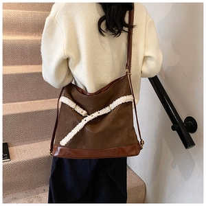 Detail of a large brown faux leather tote with plush white lamb wool cross-strap accents