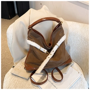 Detail view of large brown tote bag with white plush strap and golden metal buckle