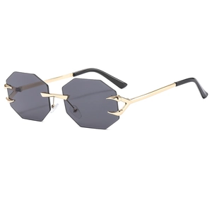 Frameless octagonal sunglasses with grey lenses and golden metal temples on white background