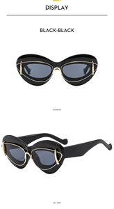 Detail view of black cat-eye sunglasses with gold metal accents and grey lenses